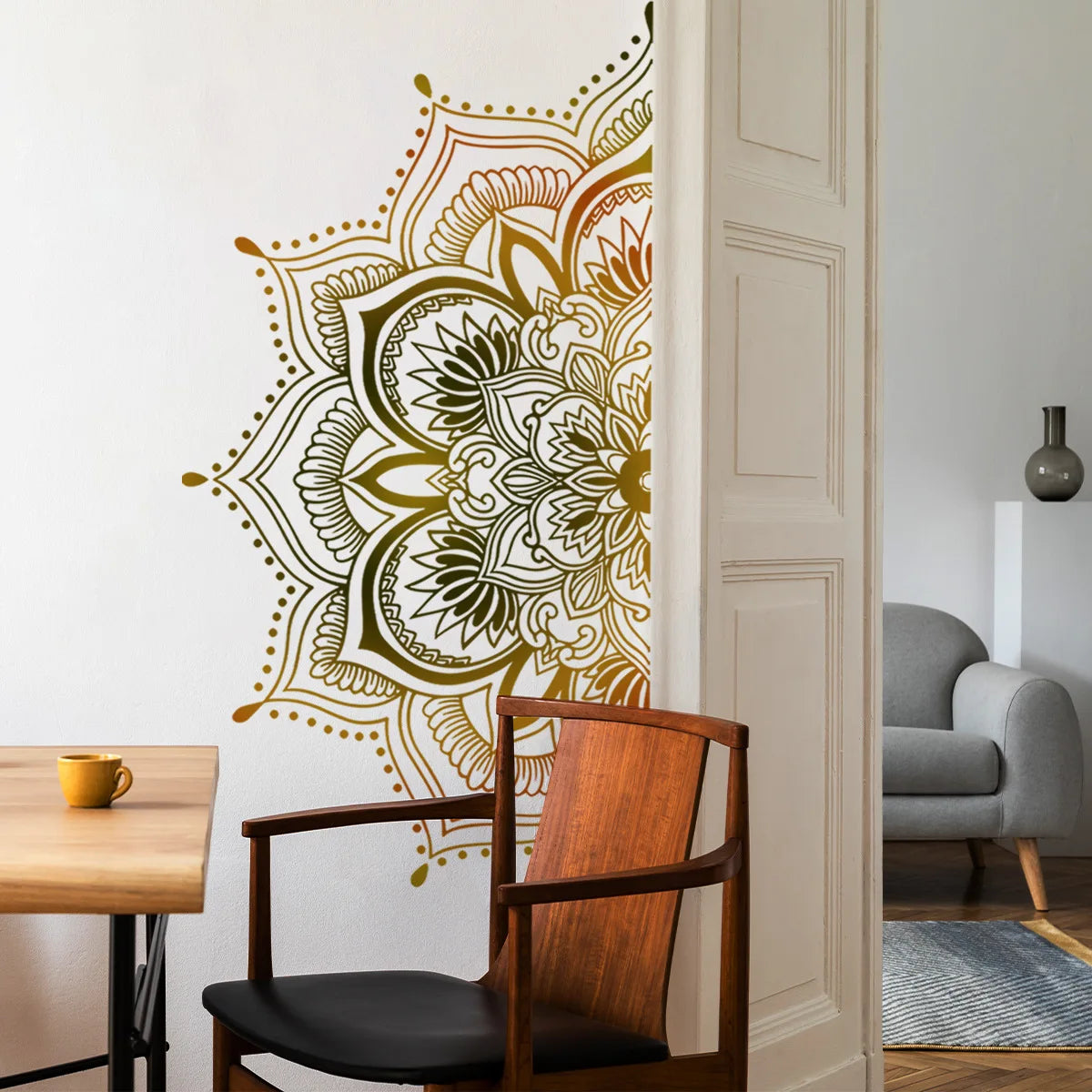 Une chaise en bois est placée à côté d'un autocollant mural représentant un lotus mandala or sur un mur blanc.
