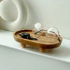 A pair of clear-framed glasses rests on a wooden tray next to a black clip.