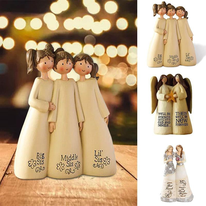 A set of three angel friendship statues in cream and beige tones standing together on a wooden surface.