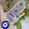Silver and blue Turkish blue evil eye hamsa hand wall hanging amulet jewelry displayed in a hand.