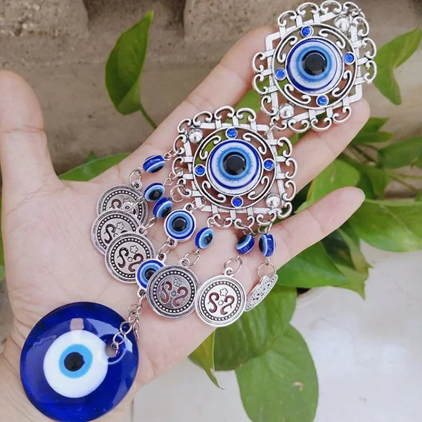 Silver and blue Turkish blue evil eye hamsa hand wall hanging amulet jewelry displayed in a hand.