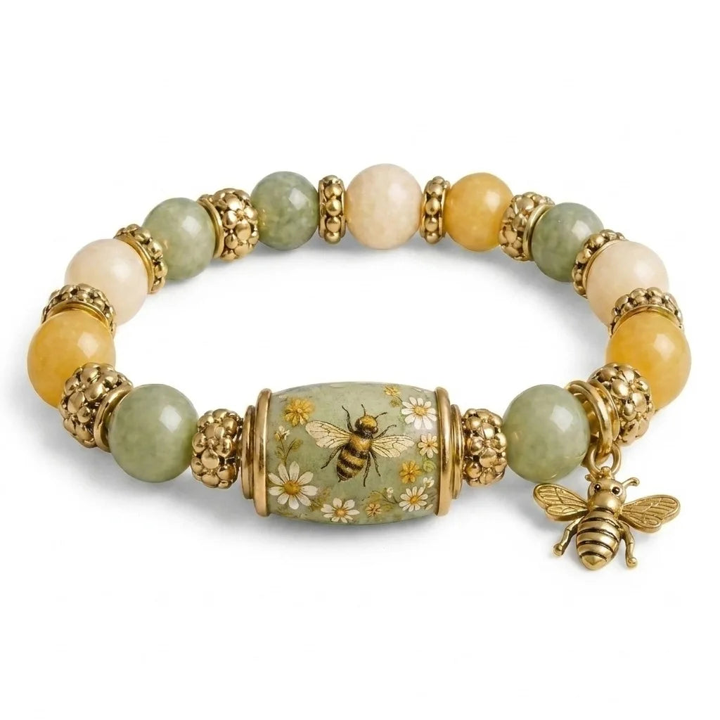 A stretch charm bracelet featuring round beads of pale green and yellow-green stones set in gold-toned metal, with a bee char