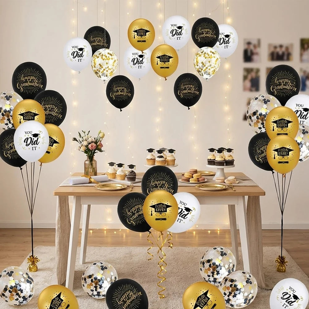 A collection of black, gold, and white graduation balloons with cap and star designs arranged on a table.