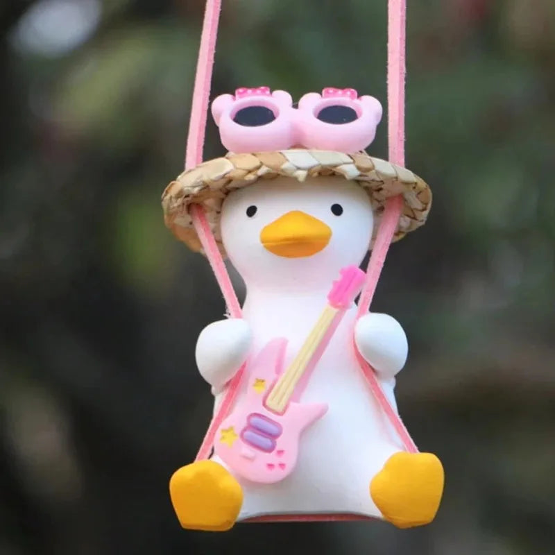 A cute pink anime duck ornament wearing a straw hat and sunglasses, suspended by a pink string.