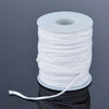 A roll of white braided cotton candle wicks for oil lamps lying on a dark surface.