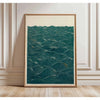 A framed canvas print featuring deep teal water texture with gold accents, displayed on a light wooden floor.