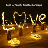 A set of LED wine bottle cork lights shaped like the word LOVE, glowing warmly on a fabric surface.