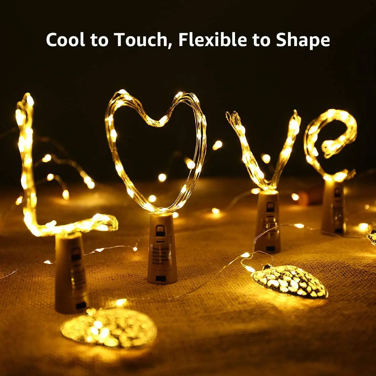 A set of LED wine bottle cork lights shaped like the word LOVE, glowing warmly on a fabric surface.