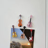 A set of five guitar-shaped fridge magnets in various colors and finishes.