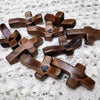 A collection of small wooden crosses with epoxy hearts for spiritual comfort resting on a white textured surface.