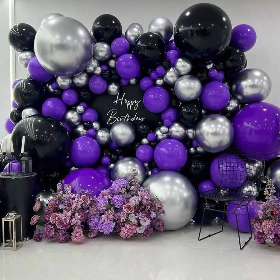 A dense arrangement of dark purple and silver latex balloons for party decor