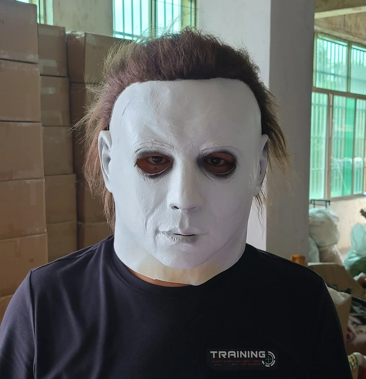 A person wearing a realistic white animal mask with dark eyes and brown hair, posing indoors.