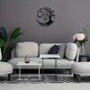 A modern living room featuring a gray wall with a black tree of life metal wall art above a light sofa and a white coffee tab