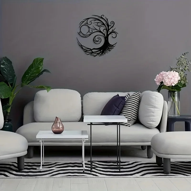 A modern living room featuring a gray wall with a black tree of life metal wall art above a light sofa and a white coffee tab