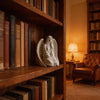 Elegante estatua decorativa de ángel blanca con alas sobre una estantería de madera.