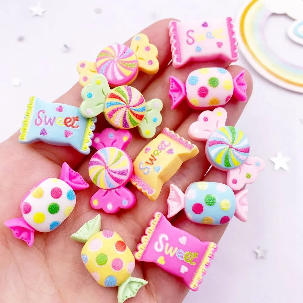 A hand holds various colorful candy resin cabochons in pink and purple hues for crafting projects.