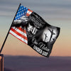 A dark banner flag featuring a hand holding an American flag and a silhouette of a cross with the text One Nation Under God.