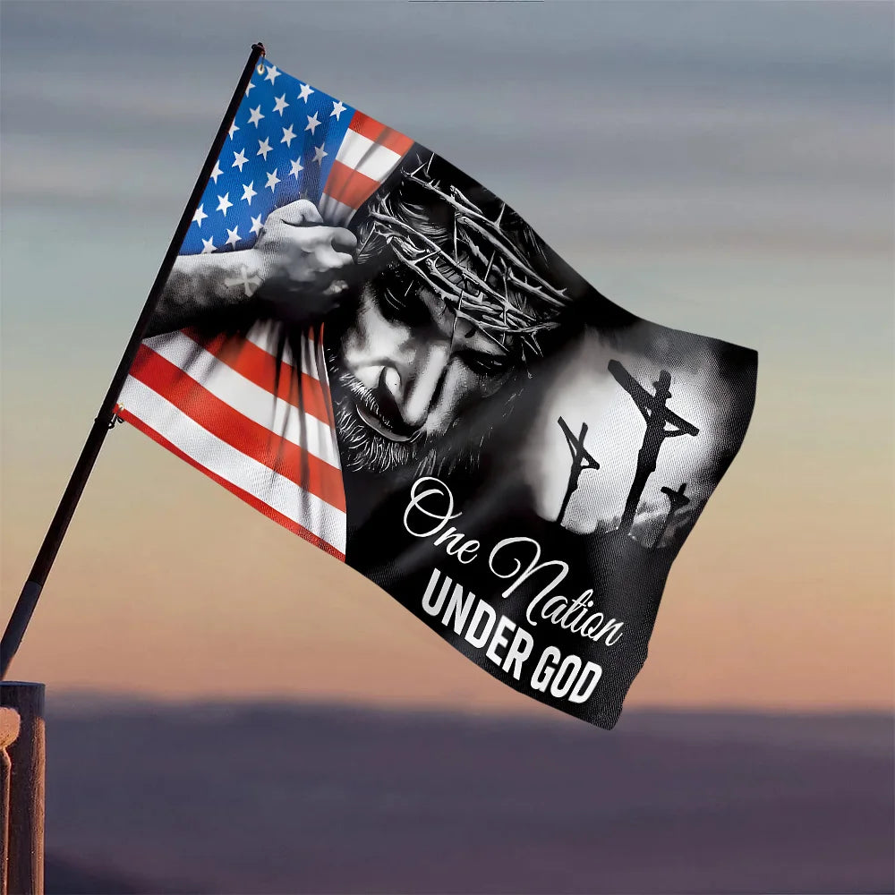 A dark banner flag featuring a hand holding an American flag and a silhouette of a cross with the text One Nation Under God.