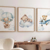 A set of three watercolor canvas prints featuring teddy bears in hot air balloons against a soft blue sky and clouds.