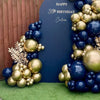 A navy blue and gold metallic balloon garland arch display against a dark background.
