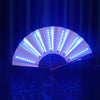 An illuminated folding hand fan with LED lights opening to reveal bright white light rays against a dark blue background.