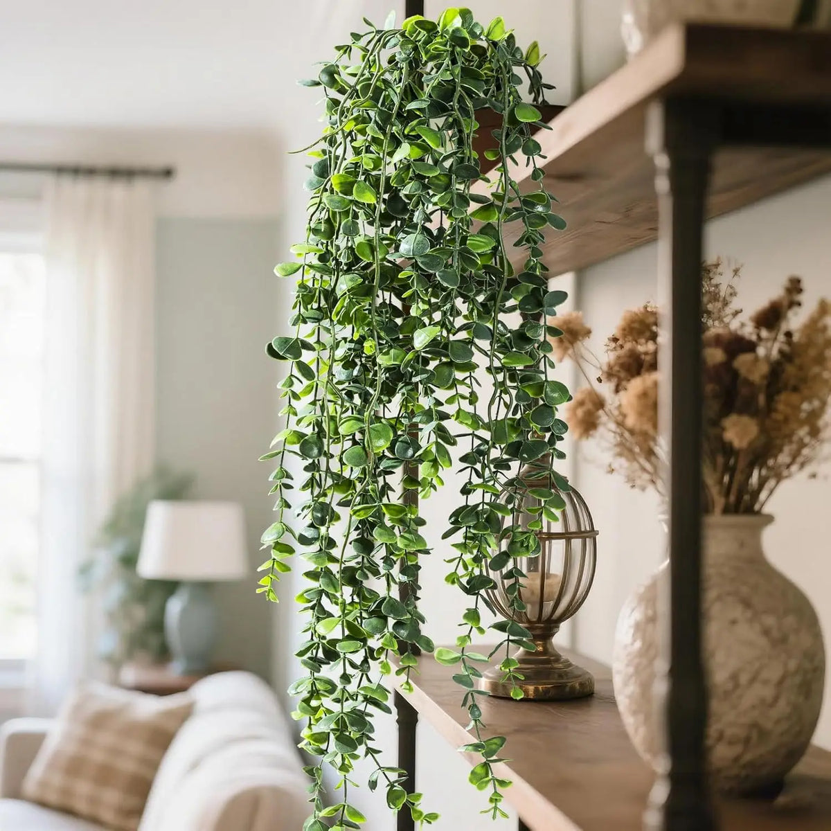 Artificial eucalyptus hanging plant with green leaves cascading down, displayed on a wooden shelf.