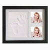 A black frame displaying a white handprint and a small photo of a baby inside.