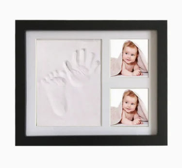 A black frame displaying a white handprint and a small photo of a baby inside.