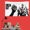 A white banner featuring the text GREEN DAY and a black silhouette of a hand making a rock fist, alongside musicians.