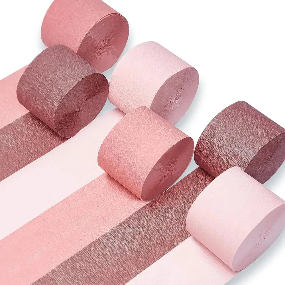 Ein Set aus rosa und mauvem Crêpepapier-Girlanden, gerollt in zylindrische Rohre.