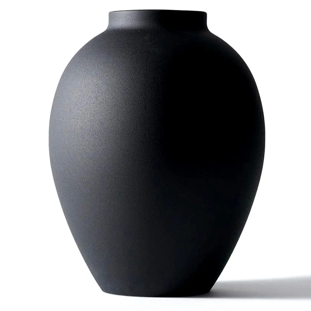 A smooth, matte black modern round metal decorative vase viewed from the side.