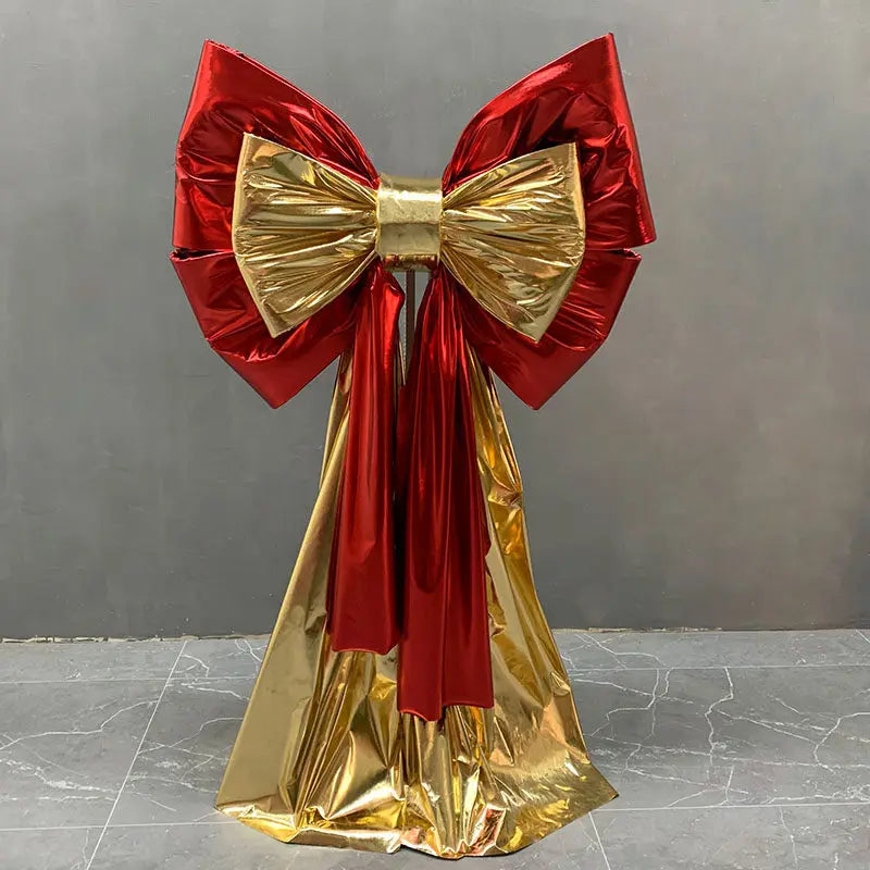 A large red and gold satin bow with a long tulle drape used for event decoration.