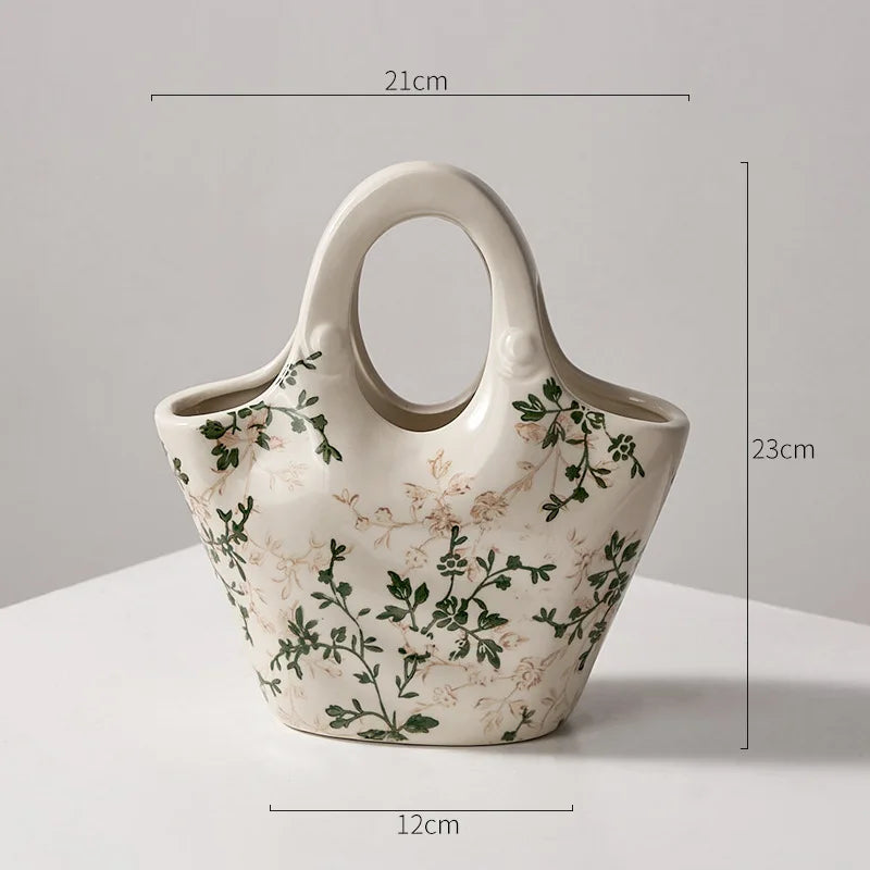 A white ceramic milk pitcher with a handle and pastoral floral design, shown from the side.