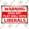 A vintage metal warning sign with red text that reads WARNING DOES NOT PLAY WELL WITH LIBERALS.