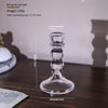 A clear glass pillar candle holder with a decorative base and a wide, round bottom.