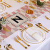 A display of gold disposable cutlery set including forks, spoons, and knives arranged on a pink and beige patterned cloth.
