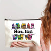 A beige canvas makeup bag with a zipper and black text reading Mtra. Itzel is held by a person with long brown hair.