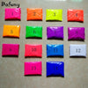A set of 14 small plastic packets containing various neon fluorescent pigment powders in different colors arranged in a grid.