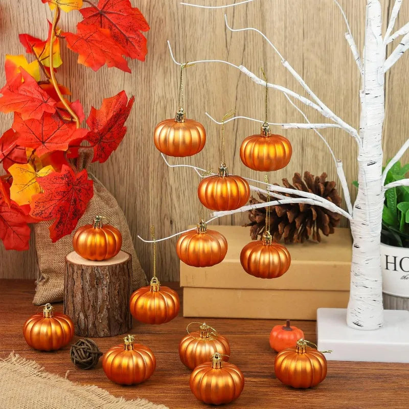 A collection of round, metallic orange pumpkin hanging ornaments displayed on a wooden surface with autumn foliage and pine c