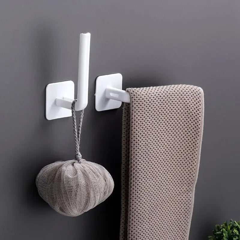 White adhesive cap holder hooks mounted on a gray wall, holding a knitted hat.