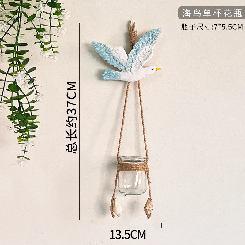 A white and blue bird-shaped decoration made of paper or fabric is suspended by twine from a glass jar.