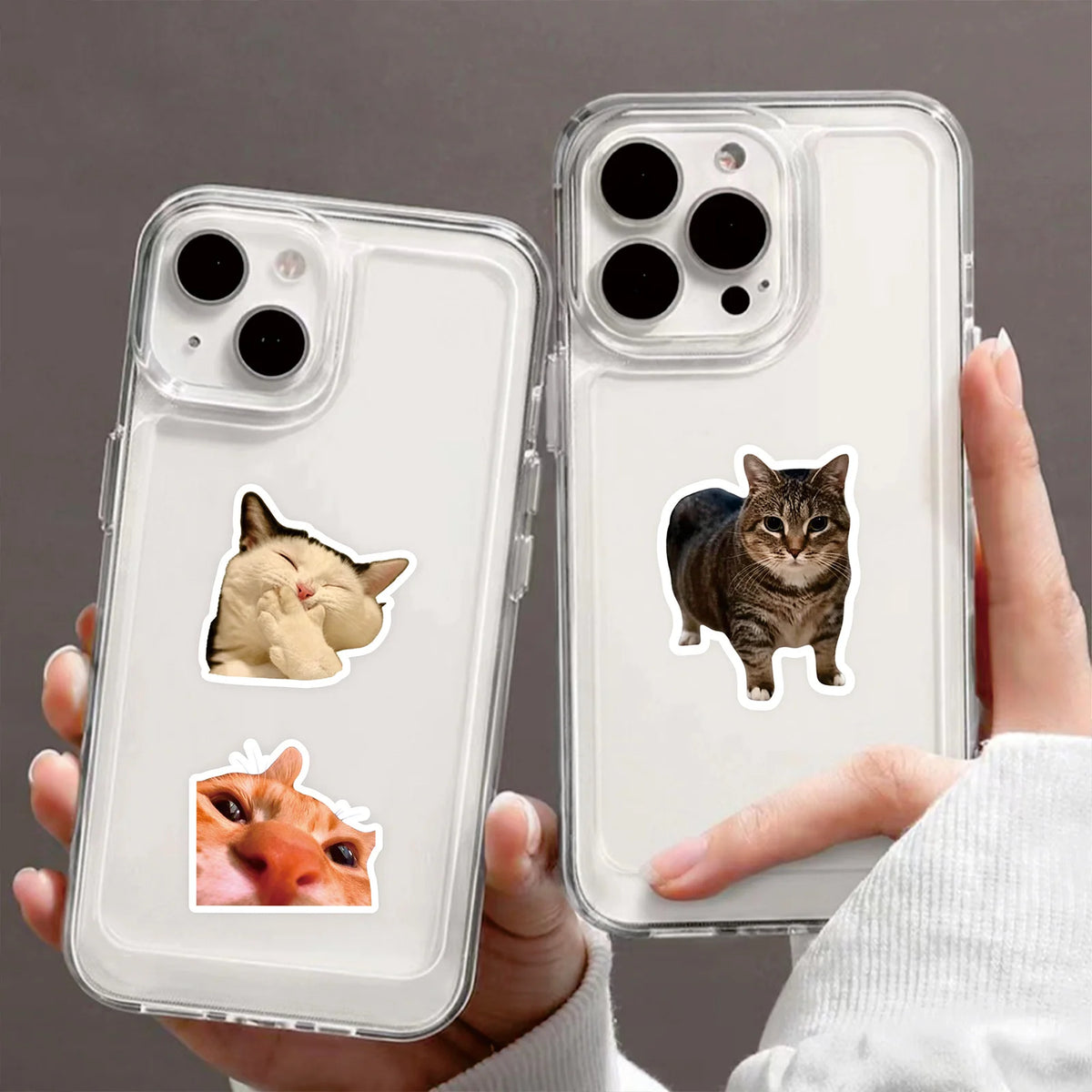 A hand holds a clear phone case featuring cartoon cat decals on the back.