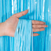 A hand holds a piece of blue metallic tinsel foil fringe curtain backdrop.
