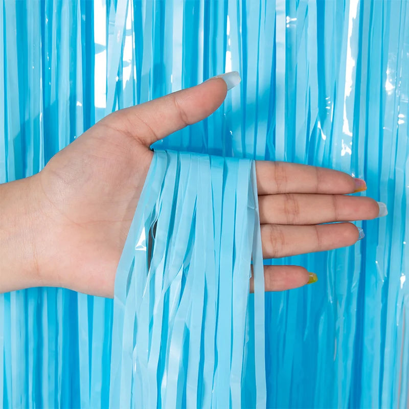 A hand holds a piece of blue metallic tinsel foil fringe curtain backdrop.