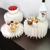 A set of five white decorative acrylic riser stands displaying various fruit and dessert items.