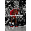 A basketball player in a red jersey is shown during a game, focusing intensely on the court.