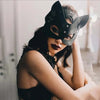 A woman wearing an elegant black fox masquerade mask with adjustable straps, looking directly at the camera.