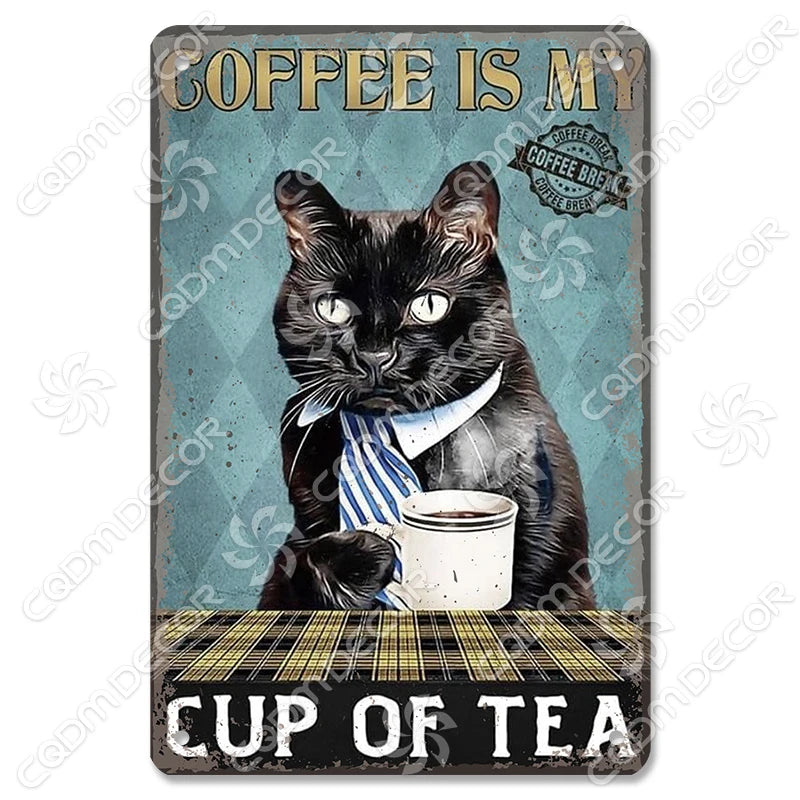 Un chat noir portant un collier rayé, assis à côté d'une tasse de thé sur une surface en bois.