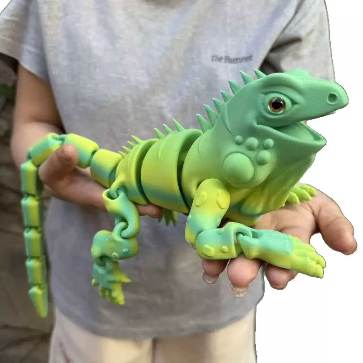 A hand holds a bright green articulated 3D printed lizard figurine for home decor.