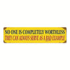 A vintage metal sign with yellow background and black text that reads No one is completely worthless they can always serve as